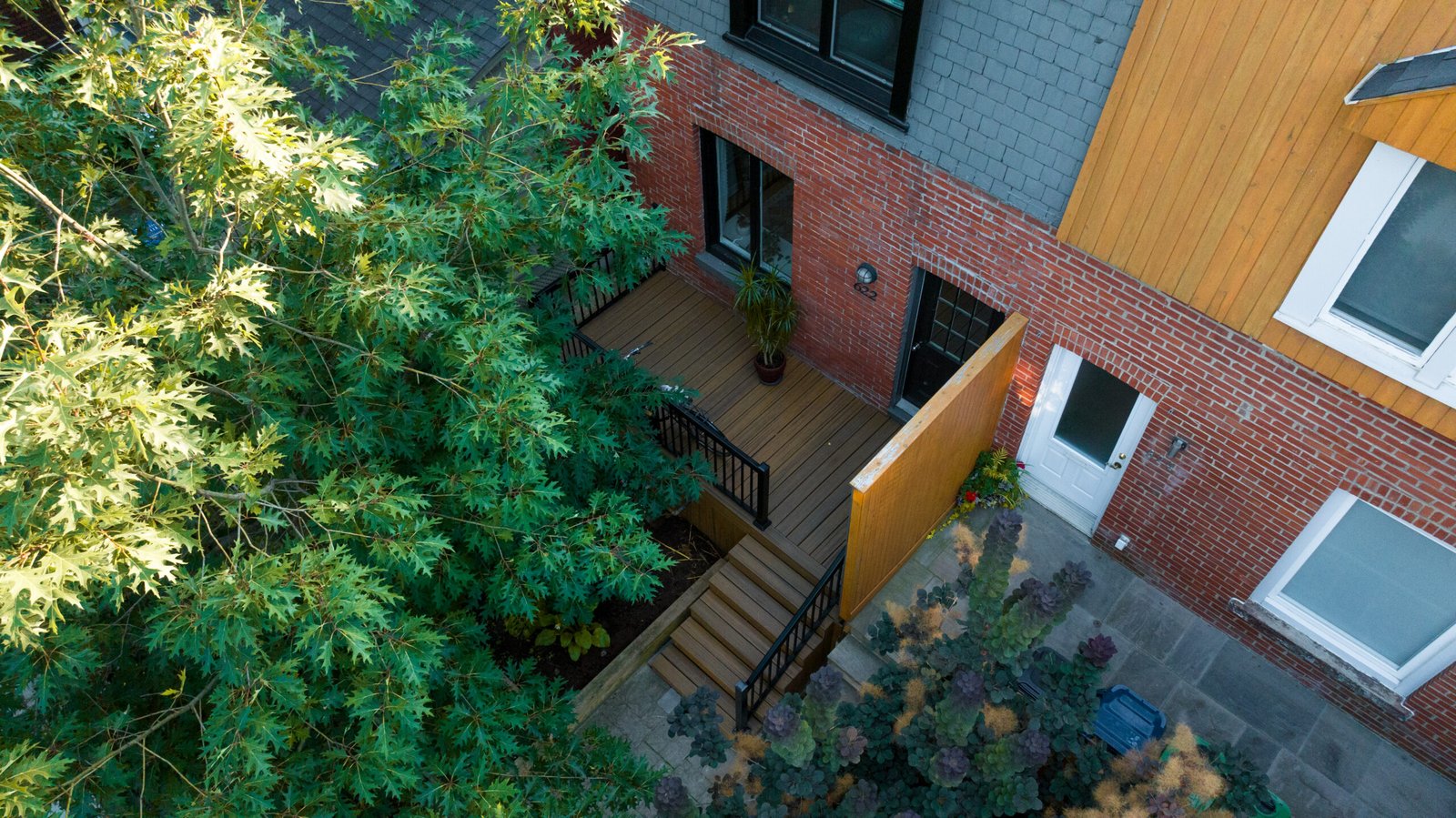 Aerial view of a completed UBL backyard — deck, privacy screen, and stone patio
