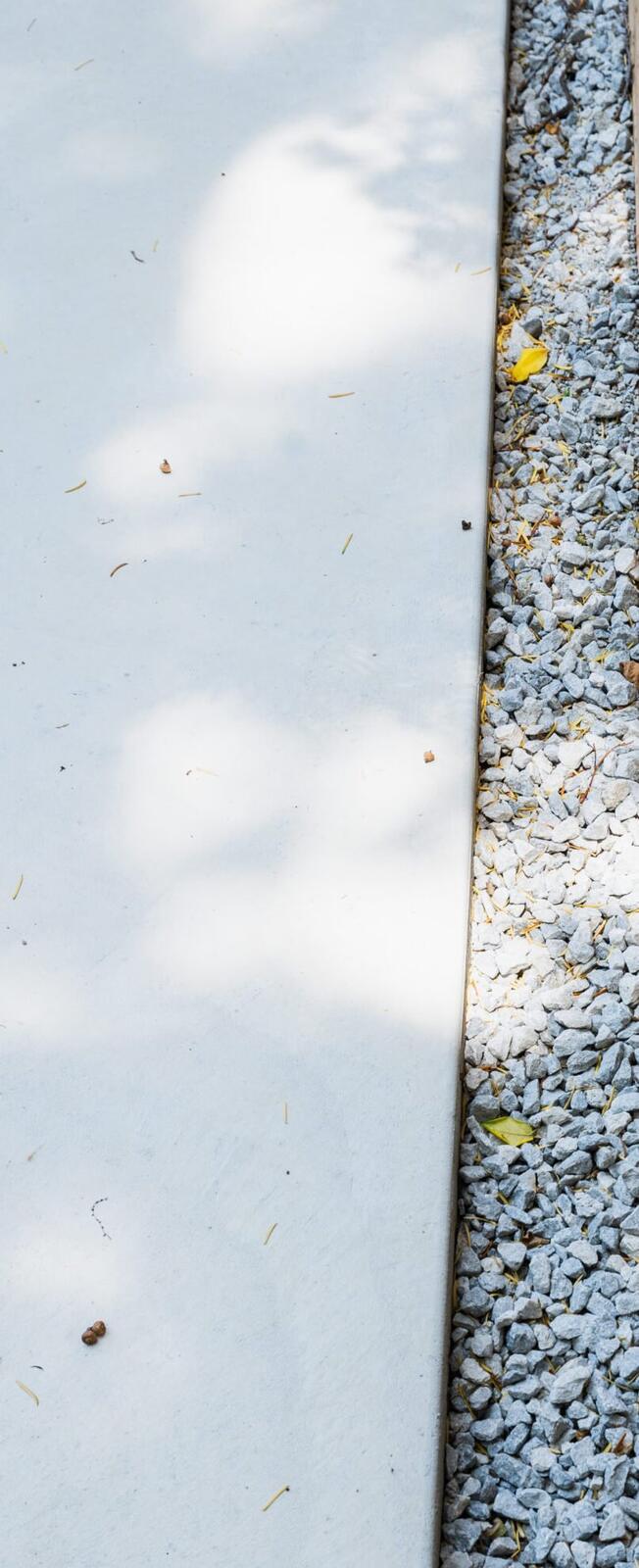 Smooth-finish concrete walkway with gravel border